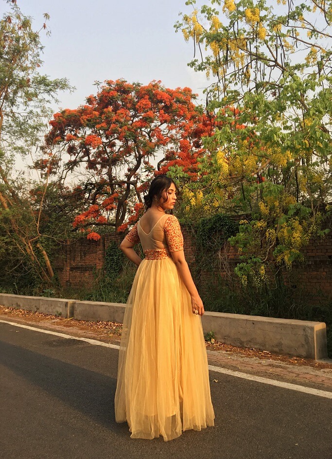 Shrizan  Wearing Golden Gown SIde Pose Trees In Back 